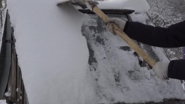 Мужчина убирает снег из колодца в деревне лопатой, много снега, зима в деревне — стоковое видео