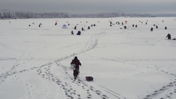 Fischer wandert auf gefrorenem See, Winterangelmeisterschaft, verschneiter See — Stockvideo