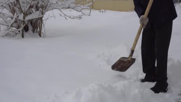 Um homem limpa a estrada da neve com uma pá, muita neve, inverno na aldeia — Vídeo de Stock