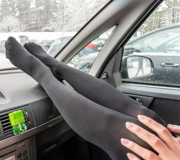 Πόδια ενός κοριτσιού με μαύρο καλσόν σε ένα ταμπλό αυτοκινήτου, κοριτσίστικα γόνατα σε καλσόν — Φωτογραφία Αρχείου