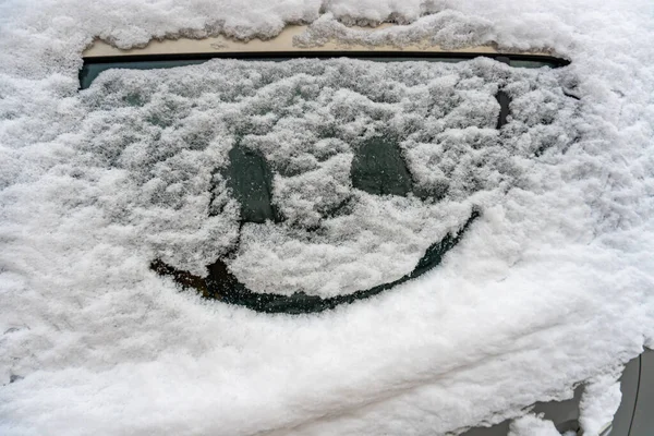 Sonrisa dibujada en el vidrio del coche en la nieve — Foto de Stock