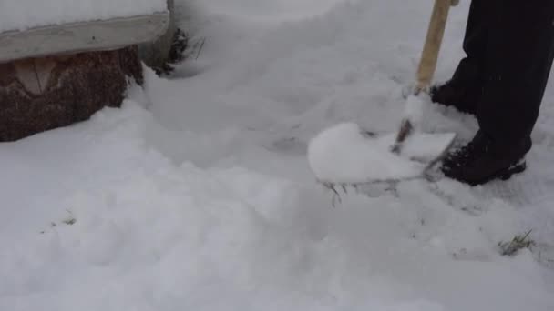 A man cleans the road from snow with a shovel, a lot of snow, winter in the village — Stock Video