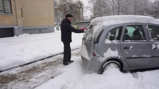 Man verwijderen van sneeuw uit de auto een natte asfalt kleur met een Broom — Stockvideo