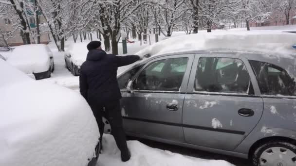 Uomo rimozione della neve da auto un colore bagnato asfalto con una Scopa — Video Stock
