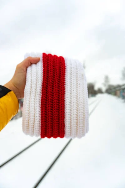 Bílo-červeno-bílá pletená šála v ruce vedle železniční silnice — Stock fotografie