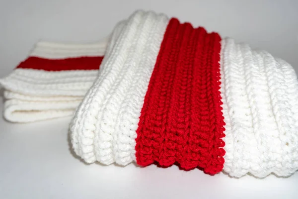 Warm knitted clothes white red white on a white background, knitted scarf