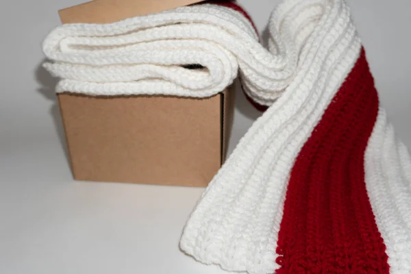 White-red-white knitted scarf in cardboard craft box on white background