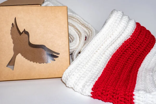 White-red-white knitted scarf and cartboard box on white background