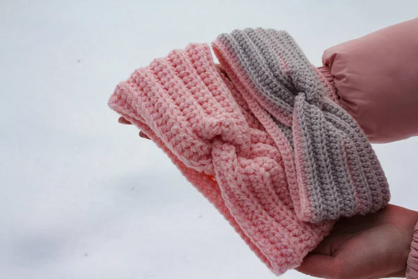 Вязаные женские повязки в руках на снежном фоне — стоковое фото