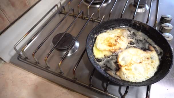 Dvě vejce jsou smažená na kamnech na obou stranách v másle na pánvi — Stock video