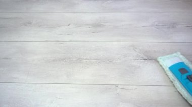 Gri kaplamalı paspasla oturma odasının yerlerini temizliyorum. Yakın plan..