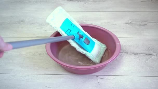 Den blauen Wischmopp in eine Schüssel Wasser geben, um später mit der Reinigung des Fußbodens zu beginnen — Stockvideo