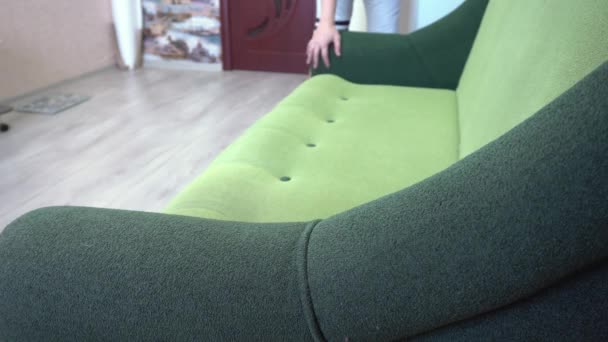 Um homem rearranja móveis em uma sala, movendo o sofá, mudanças no interior, um cara muda a situação em um apartamento — Vídeo de Stock