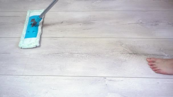 Muž čistí podlahy mopem na šedém laminátovém povrchu. Detailní záběr — Stock video