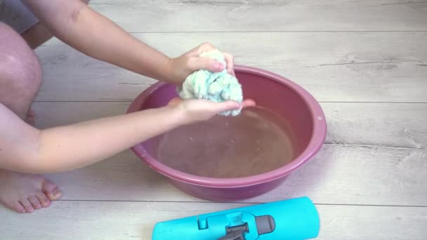 Ein Mann spült ein Wischmopp-Tuch in ein Becken mit Wasser und drückt es dann aus und legt es wieder auf den Wischmopp — Stockvideo