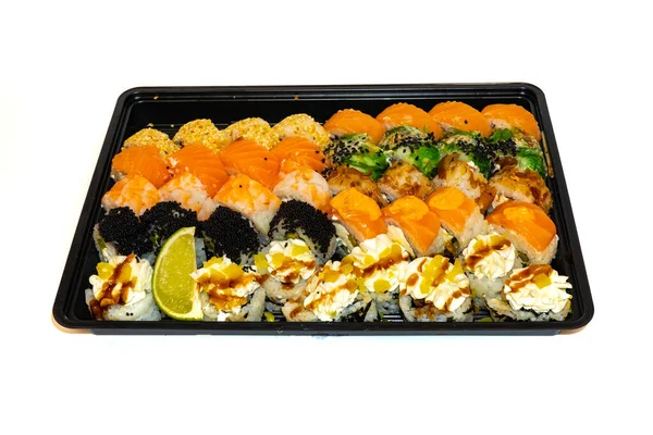 Sushi set med rullar philadelphia, Kalifornien, bonito, tonfisk, sesam, svart tobico, chuka sallad, räkor och färskost ligger i svart låda för leverans. Japanskt kök, europeiska sushirullar — Stockfoto