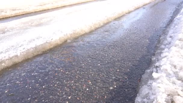 Une piste de voiture dans la neige fond sous le soleil du printemps et expose l'asphalte — Video