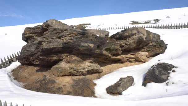 Eingezäunter Steinfelsen inmitten schneebedeckter Berge im Winter vor blauem Himmel — Stockvideo