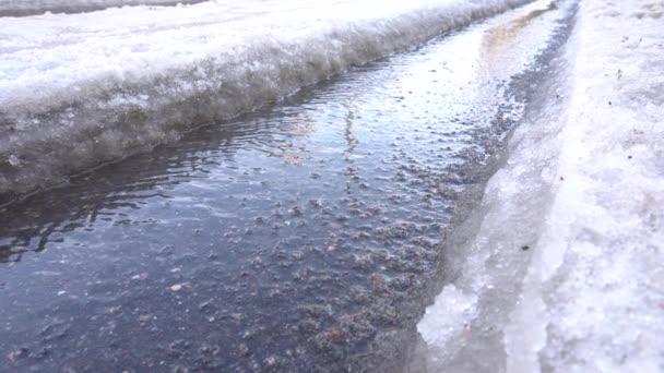 Neve derrete e flui pela pista do carro, o fluxo de mola flui no asfalto — Vídeo de Stock
