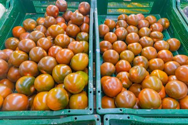 Piyasadaki plastik yeşil kutuda sulu siyah domatesler. Domates arkaplanı