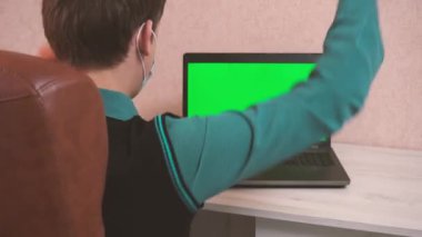 Bir adam video konferansında koruyucu bir maskeyle dans eder, bir dizüstü bilgisayarda krom anahtar ve bir adam neşe içinde dans eder.