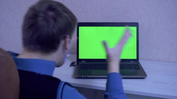 Koruyucu yüz maskesi takan bir adam video konferansında uzaktan bağlandığı için duygusal olarak kızgın ve yeşil ekranlı bir dizüstü bilgisayara yumruk atıyor. — Stok video