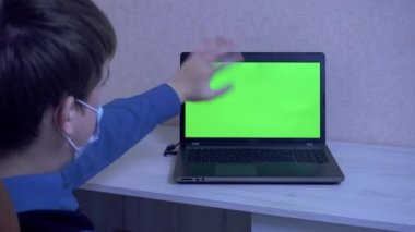 Koruyucu maskeli bir adam video konferansında iletişim kuruyor ve elleriyle işaret ediyor. Salgın sırasında uzaktan iletişim kuruyor.