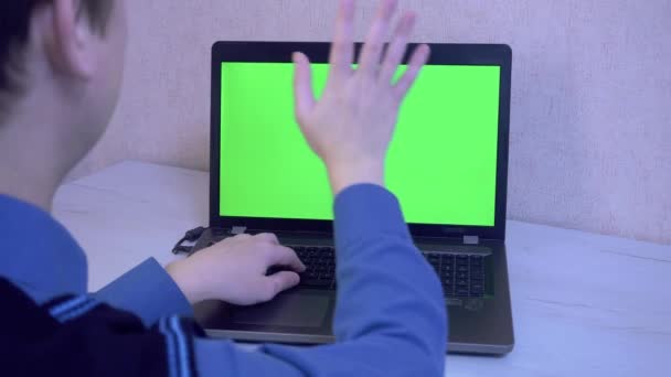 Un hombre saluda a sus colegas por vídeo llamando a un ordenador portátil y le recuerda que se ponga una máscara protectora, una pantalla de monitor verde — Vídeos de Stock