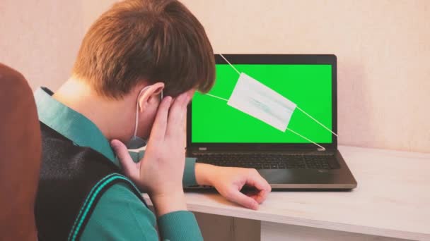 Koruyucu yüz maskesi takmış bir adam video konferansında uzaktan bağlandığı için duygusal olarak kızgın ve yeşil ekranlı bir dizüstü bilgisayara yumruk atıyor. — Stok video
