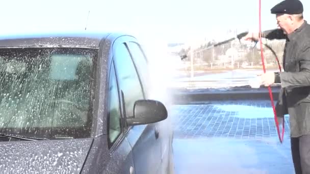 Auto wassen en detailleren. Een man wast een auto in z 'n eentje bij een handmatige wasstraat. — Stockvideo