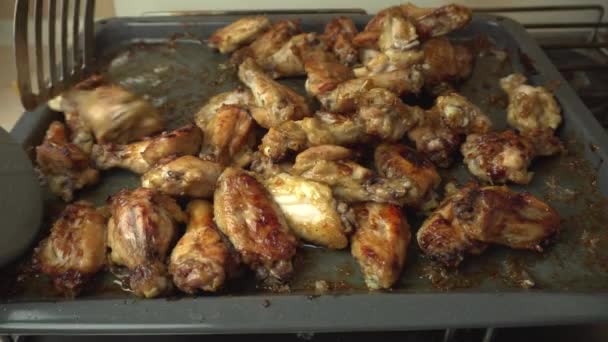 Nybakade kryddiga kycklingvingar skalas av från bakplåten med en köksstekspade — Stockvideo