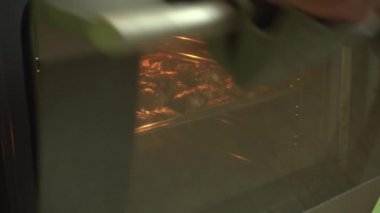 Fırında pişirilmiş baharatlı tavuk kanatları kirli bir fırından çıkartılır.