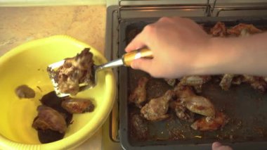 Taze pişmiş baharatlı tavuk kanatları sıcak bir yemek tepsisinden bir kase barbekü sosuna aktarılır.