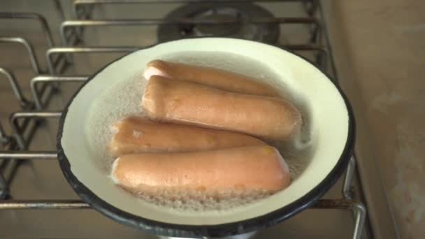 Enchidos são cozidos em uma tigela no fogão, salsichas ferventes — Vídeo de Stock