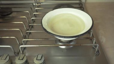 Ocakta bir kase su, kaynar suda kaynatmak için çiğ sosisler suya batırılır.