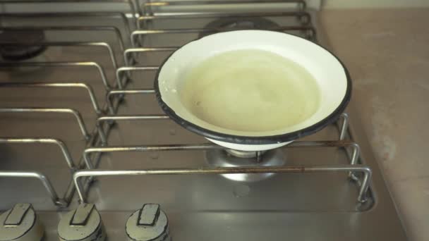 Un bol d'eau sur la cuisinière, les saucisses crues sont trempées dans de l'eau pour bouillir dans de l'eau bouillante — Video