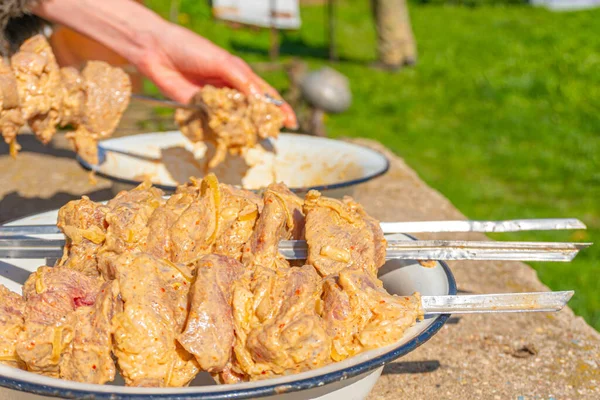 La chica pone la carne marinada en pinchos para cocinar en la parrilla — Foto de Stock