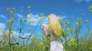 Genç ve güzel bir kız hasır bir şapkanın arkasına saklanıyor ve yazın çiçek açan bir tecavüz tarlasında flört ediyor.