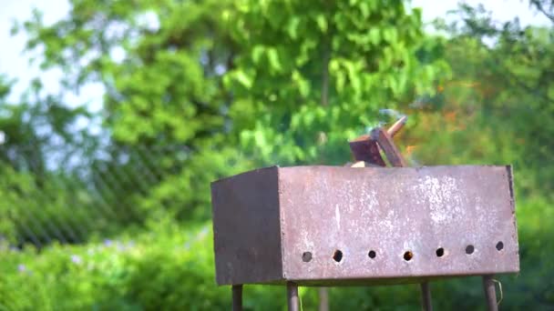 Metalen roestige zelfgemaakte grill brandt en rookt in de achtertuin op een zonnige dag — Stockvideo