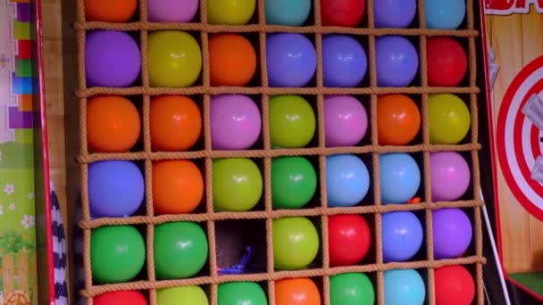 Atracción de globo en el parque de atracciones, Lanzamiento de dardos de globo serie juego de habilidad de carnaval, Flying dardos flecha perfora un globo de colores, atracción con globos de colores en el parque — Vídeos de Stock