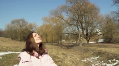 Pembe ceketli bir kız bahar parkında ağır çekimde iplik fırlatıyor.