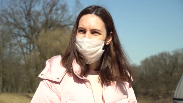 Une fille dans un pull rose regarde au loin et touche un jouet de poulpe tricoté sur un fond d'arbres d'automne — Video