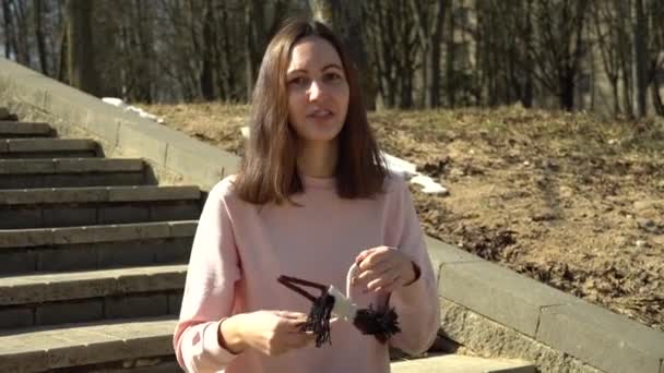 Een mooi meisje in een roze blouse speelt met een gebreid speelgoedpaard en vertelt de haak proces en veel plezier en glimlachen — Stockvideo