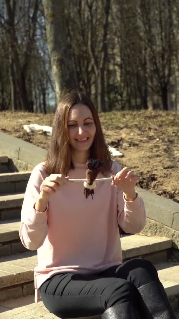 Une belle fille en chemisier rose joue avec un cheval jouet tricoté et s'amuse et sourit, vidéo verticale — Video