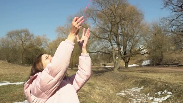 Ein Mädchen in pinkfarbener Jacke wirft in einer herbstlichen Frühlingspark-Zeitlupe einen Fadenball nach oben — Stockvideo