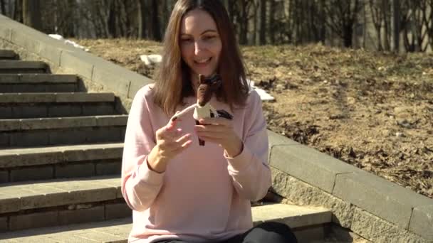 Een mooi meisje in een roze blouse speelt met een gebreid speelgoedpaard en vertelt de haak proces en veel plezier en glimlachen — Stockvideo