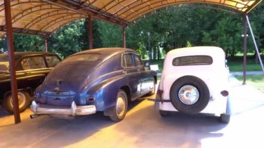 Belarus, Dukora - 13 Ağustos 2021: Parktaki Sovyetler Birliği 'nden kalma eski arabaların altında tozlu klasik arabalar duruyor