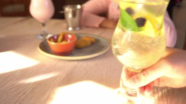 Hand nimmt einen erfrischenden Cocktail in ein Glas mit Eis, Zitrone, Minze, Soda und Brombeeren, dann trinkt und stellt das Glas auf den Tisch, Familienfrühstück — Stockvideo