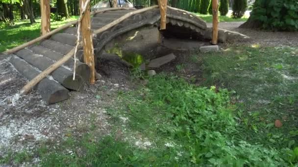 Hermosa pasarela semicircular de madera sobre el arroyo en el parque, el arroyo fluye bajo el puente de troncos de madera — Vídeos de Stock