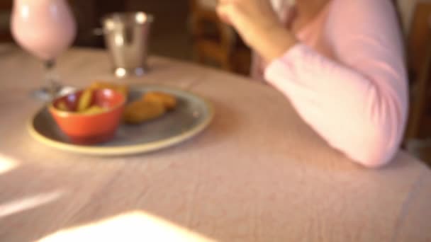 Hand neemt een verfrissende cocktail in een glas met ijs, citroen, munt, frisdrank en bramen, drinkt en zet het glas op tafel, familie ontbijt — Stockvideo